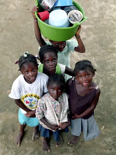 Unas niñas regresan del río después de lavar los cacharros de la cocina tras el almuerzo.